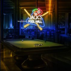 a pool table in front of a neon sign that says jack's pool hall