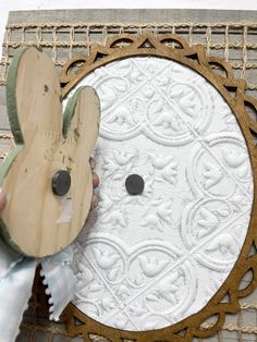 a person holding a wooden object in front of a paper doily with an animal on it