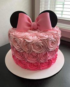 a minnie mouse cake is decorated with pink roses