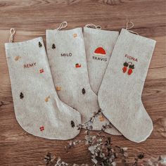 three pairs of personalized christmas stockings on a wooden table with cotton flakes around them