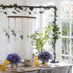 a dining room table set with plates and flowers on it, hanging from the ceiling