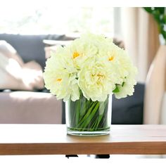 a vase filled with white flowers sitting on top of a table next to a couch