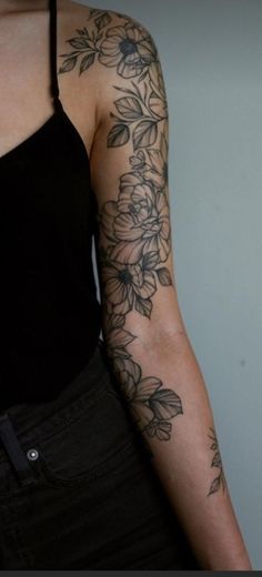 a woman's arm with flowers and leaves tattooed on the back of her arm