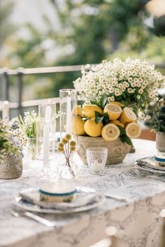 the table is set with lemons and flowers