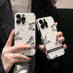 two women holding up their cell phones with butterfly designs on them, one is white and the other is black