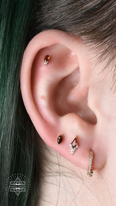 an ear with three different piercings attached to it's sides and the other side