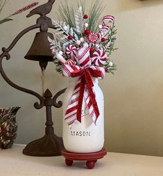 a mason jar filled with candy canes and greenery sitting on a table next to a lamp