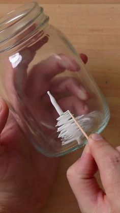 a person holding a toothbrush in a jar