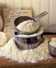 three metal bowls filled with flour on top of a wooden table