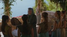 a group of women standing next to each other in front of a body of water