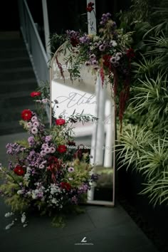 a mirror sitting on top of a table next to flowers and plants in front of it