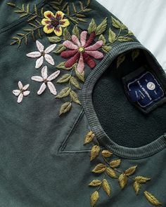 an embroidered jacket with flowers on it and a cell phone laying next to the pocket