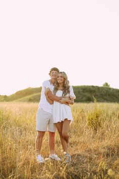 two people standing in a field hugging each other