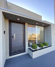 an entrance to a modern home with two planters