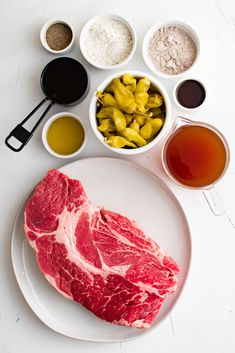 raw meat on a plate with spices and seasonings around it, along with other ingredients