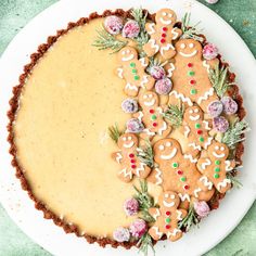 a white plate topped with a pie covered in gingerbread cookies and frosted pretzels