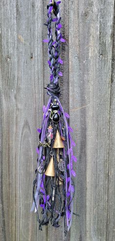 a purple and black bell hanging from a wooden fence with bells attached to it's sides