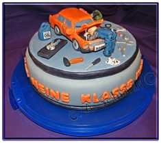 a birthday cake for a mechanic on top of a blue plate with an orange car and tools