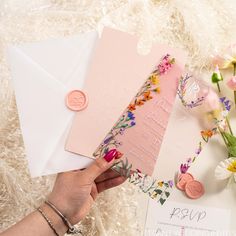 a person holding an envelope with flowers on it next to some cards and other items