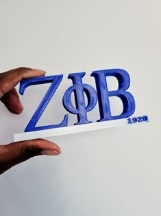 two hands holding up the letters that spell out zob, which appear to be blue