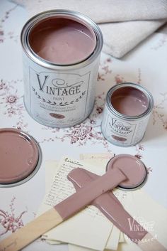 a can of pink paint sitting on top of a table next to some papers and a brush