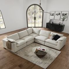 a living room with a large sectional couch and coffee table on the floor in front of an arched window