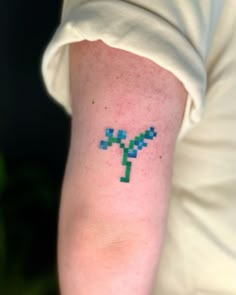 a person's arm with a pixelated cross tattoo on the left side of their arm