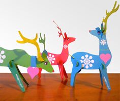 three paper deer standing next to each other on a table