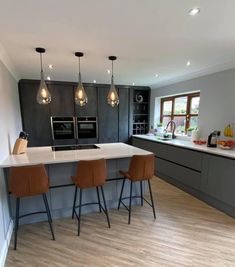 a kitchen with three bar stools next to an island in the middle of it