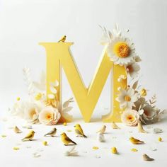 the letter m is surrounded by flowers and small bird figurines on a white surface