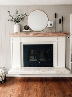 a living room with a white fireplace and wooden floors