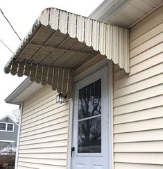 a house with a white front door and a metal awning on the side of it