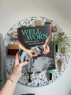 a person holding up a book in front of a wall decoration