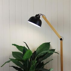 a black lamp sitting on top of a wooden table next to a green potted plant