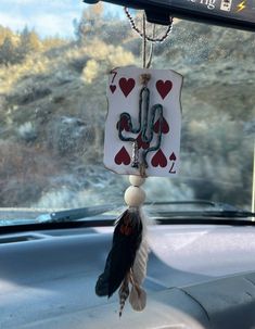 a car dashboard with a hanging decoration in the shape of a cactus and hearts on it