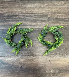 two green wreaths on top of a wooden table