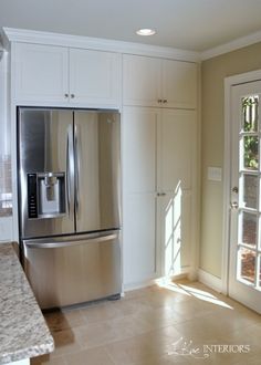 a stainless steel refrigerator in a kitchen with white cabinets and granite counter tops, along with marble flooring