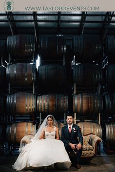 a bride and groom sitting in front of barrels