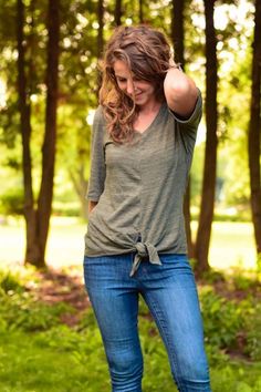 a woman standing in the grass with her hand on her head