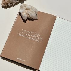 an open book sitting on top of a table next to a piece of paper and some rocks