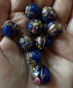 several blue and gold beads in the palm of someone's hand