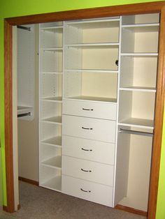 an empty closet is shown with white drawers and shelves on each side, in front of a green wall