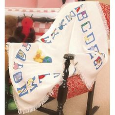 a baby blanket sitting on top of a rocking chair next to a teddy bear and other toys