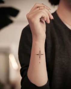 a woman's wrist with a small cross tattoo on the left side of her arm