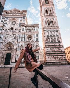 a woman is posing in front of a cathedral