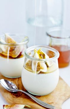 two jars filled with pudding on top of a wooden cutting board next to spoons