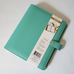 a green binder sitting on top of a white table next to a blue book