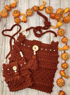 two crocheted purses sitting on top of a wooden table next to pumpkins