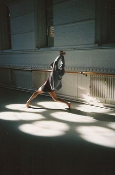 a man is running in the middle of an empty room with long shadows on the floor