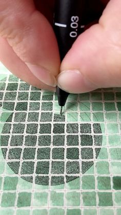 a person using a marker to draw on a piece of paper with squares and circles